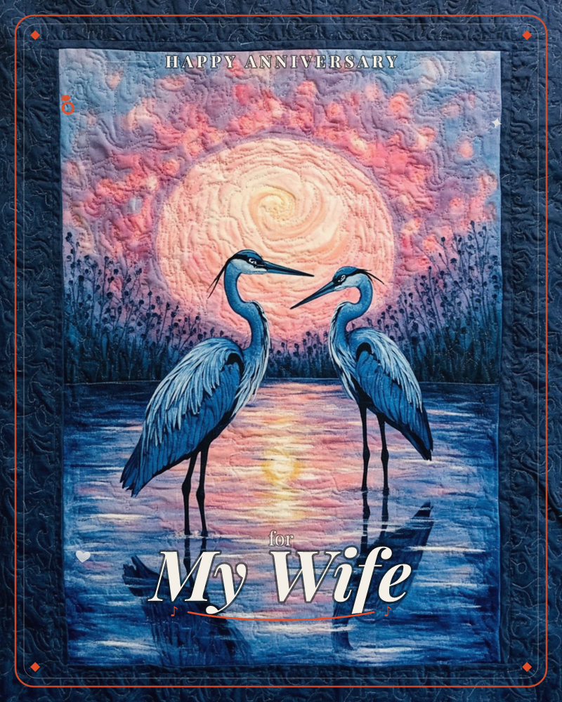 Two great blue herons stand face to face in still water, framed by tall reeds and a huge glowing pink-gold sun rising behind them, a anniversary e-card design