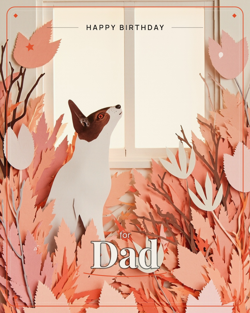 A paper-craft fox with a brown-and-white face sits amid a sculpted thicket of autumn leaves and bare branches, gazing up at a glowing windowpane, a birthday e-card design