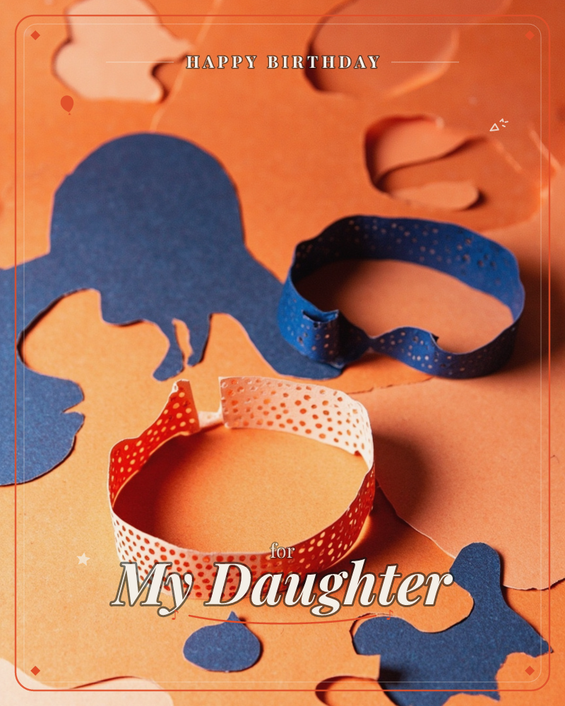 A close-up still life of paper-craft offcuts: two speckled paper loops, one navy and one peach, rest atop scattered cut-out scraps of orange and dark…, a birthday e-card design
