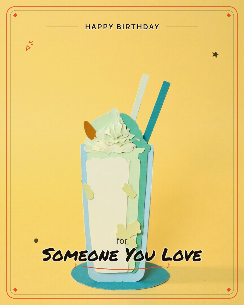 A tall milkshake glass built entirely from layered paper cutouts stands against a bright yellow backdrop, complete with a swirl of paper whipped cream…, a birthday e-card design