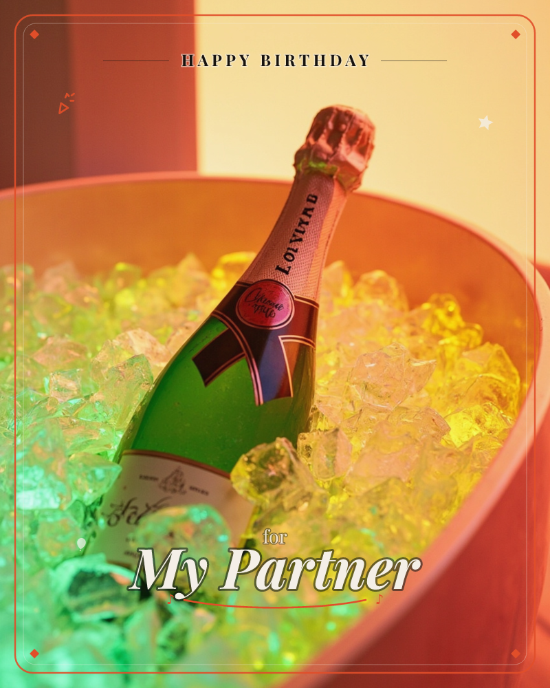A bottle of champagne rests tilted in a copper bucket packed with glowing ice, lit from within by a warm amber and green light, a birthday e-card design