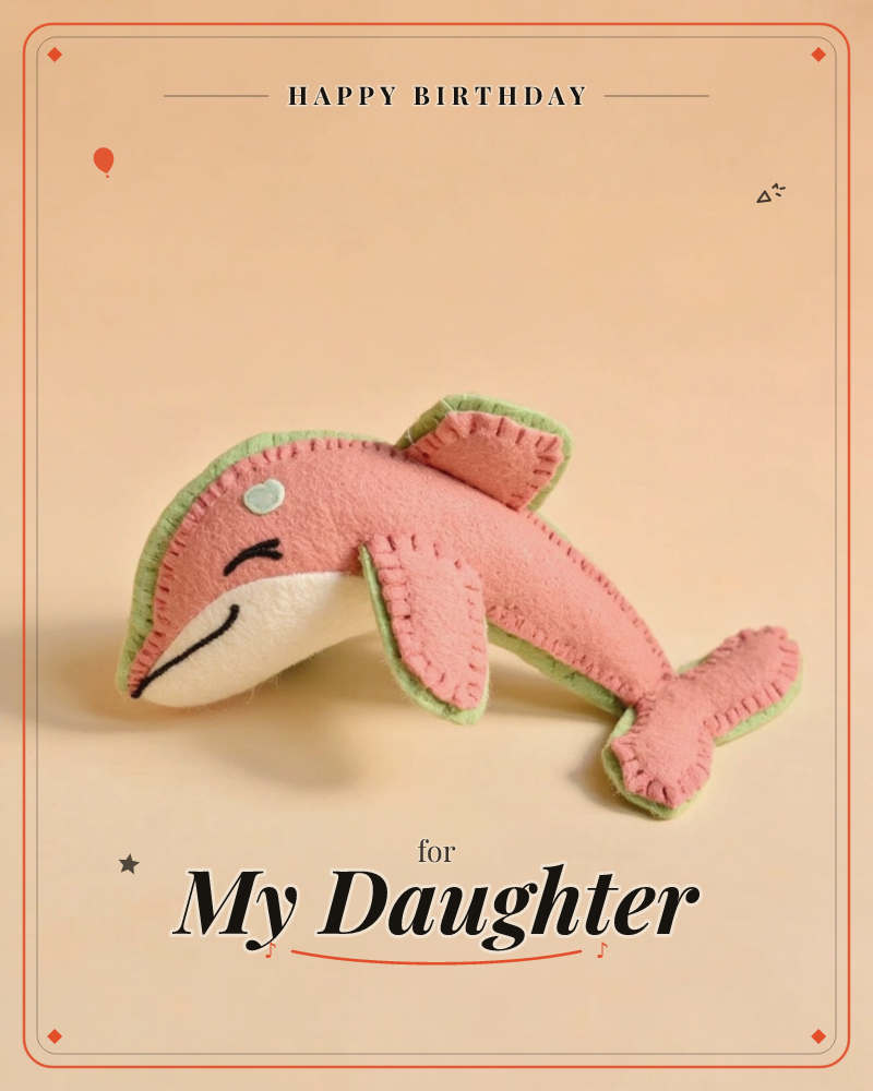 A plush felt dolphin sits against a soft peach backdrop, its coral-pink body edged in green blanket-stitch seams and a cream-white belly, a birthday e-card design