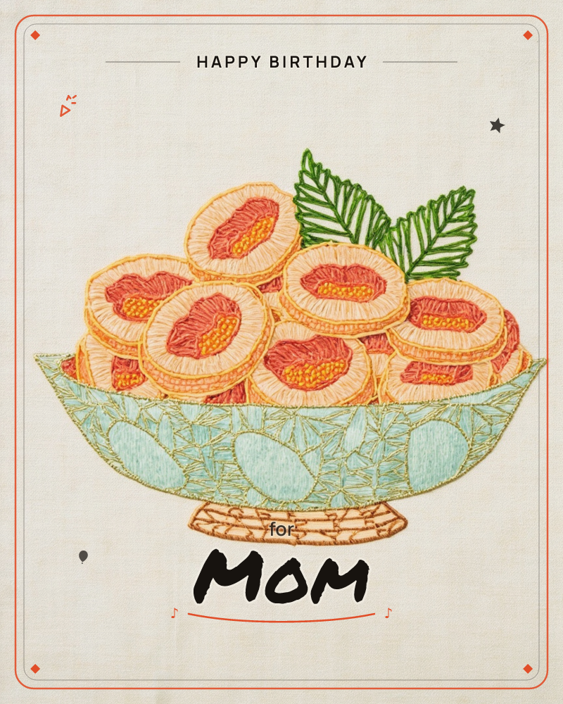 An embroidered bowl overflows with halved peaches, their coral-pink centres stitched in radiating threads and topped with two broad green leaves, a birthday e-card design