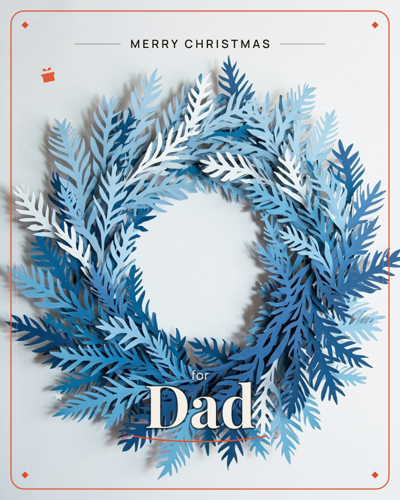 A wreath built entirely from layered paper fern fronds in shades of blue and white, arranged in a full circle against a plain pale grey background, a christmas e-card design