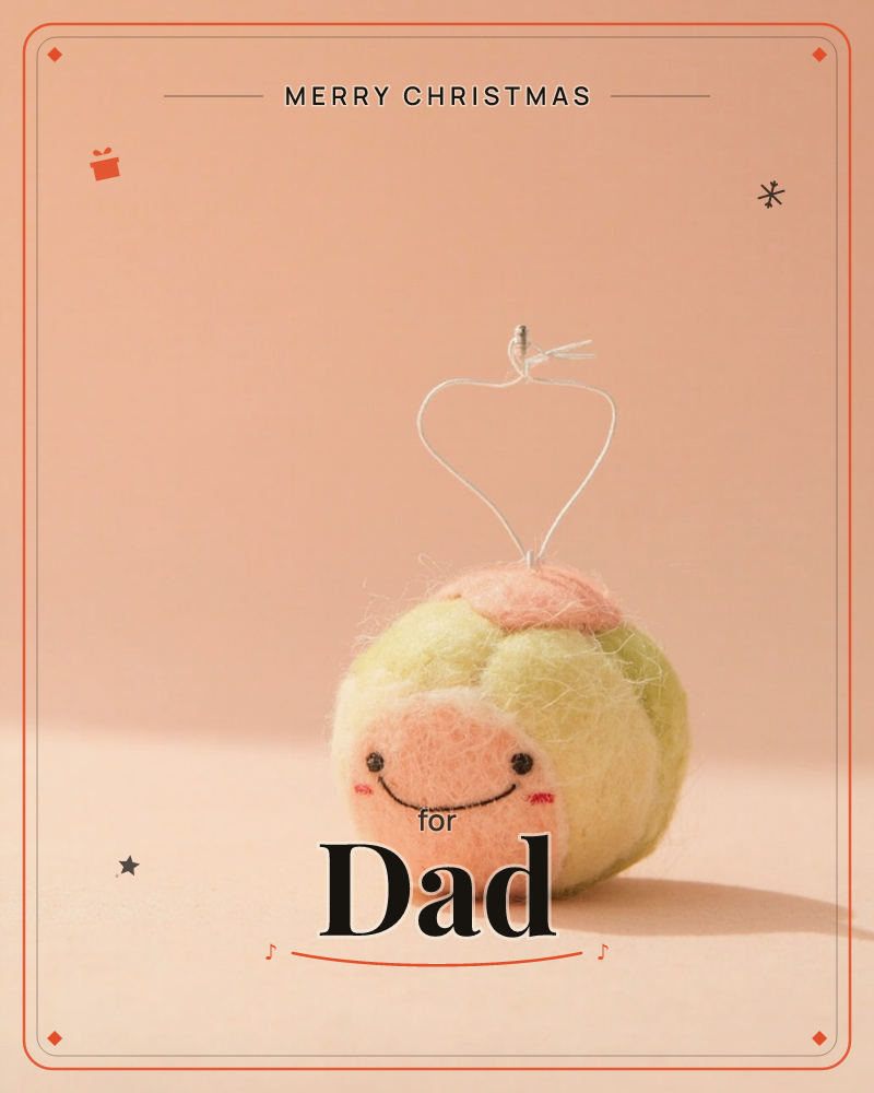 A small felted ornament shaped like a round fruit sits against a soft peach backdrop, its wool fibres blending pale yellow and blush pink, a christmas e-card design