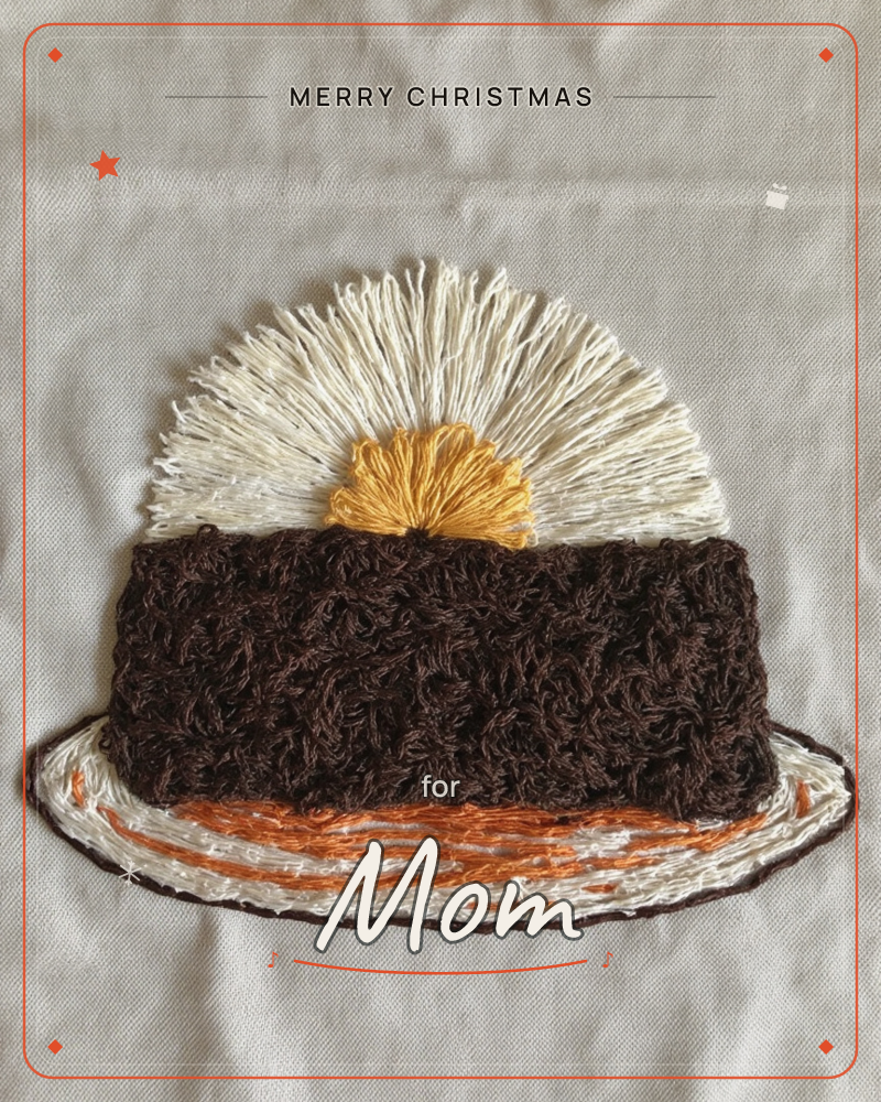 An embroidered illustration on natural linen shows a thick slice of chocolate cake topped with a swirl of whipped cream and a golden dollop, sitting on…, a christmas e-card design
