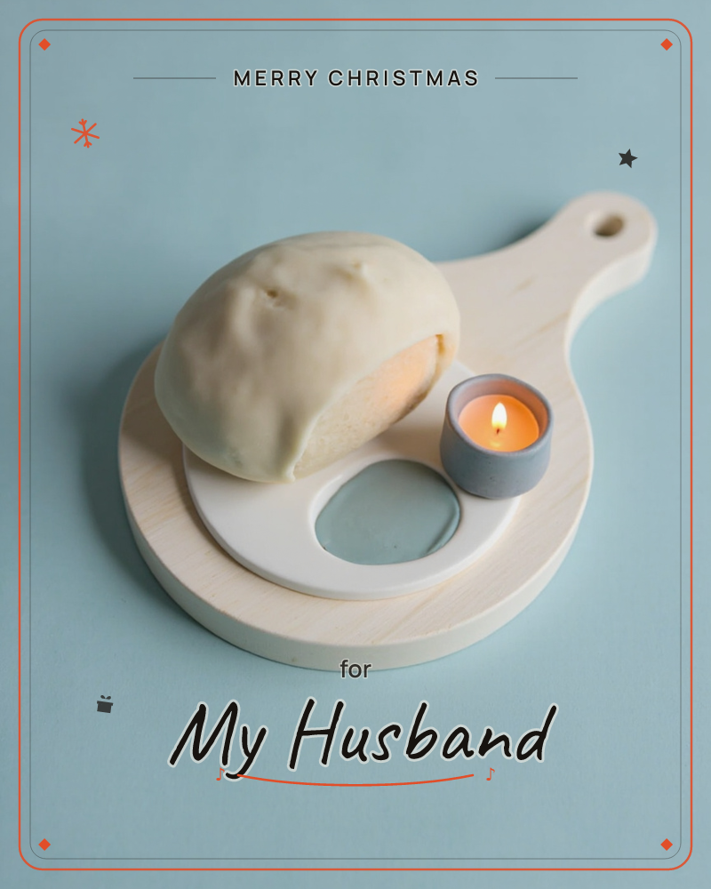 A round loaf of bread with a torn, golden-crusted edge sits on a small wooden paddle board against a soft blue background, a christmas e-card design