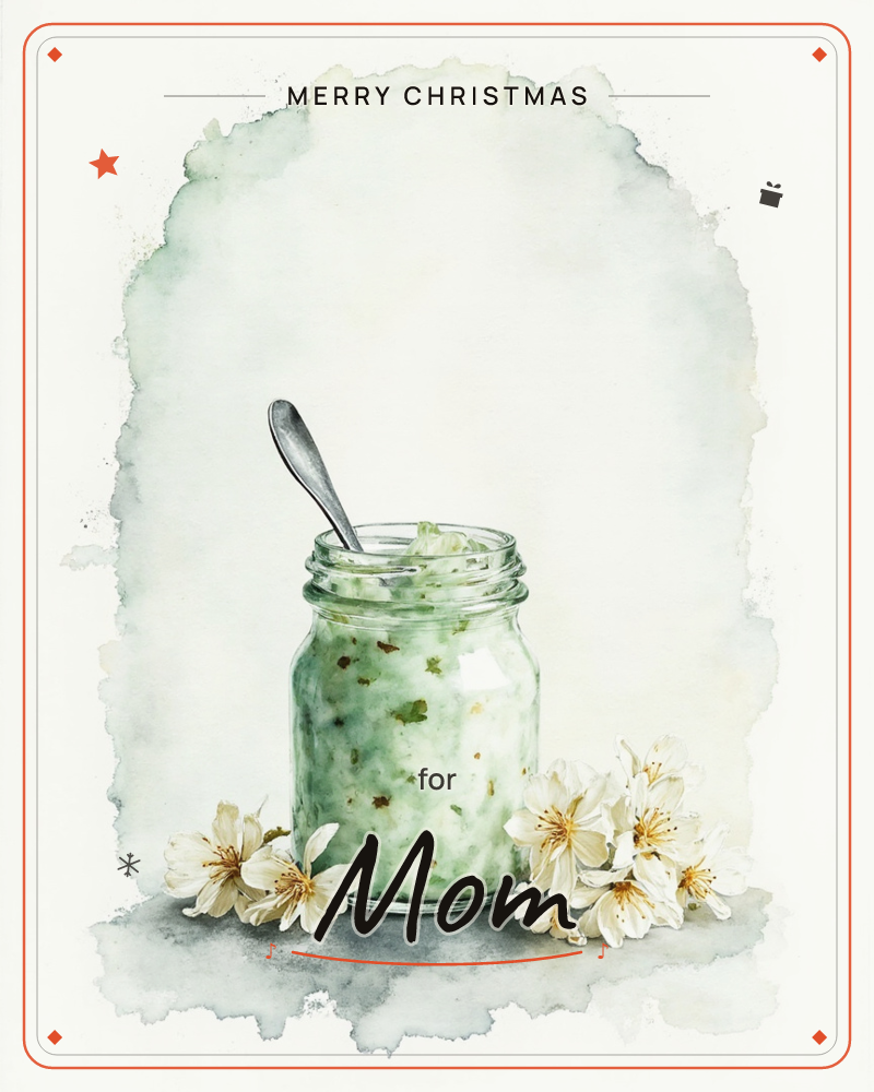A glass jar filled with a flecked green preserve sits on a pale surface, a spoon tucked inside as if just used, a christmas e-card design