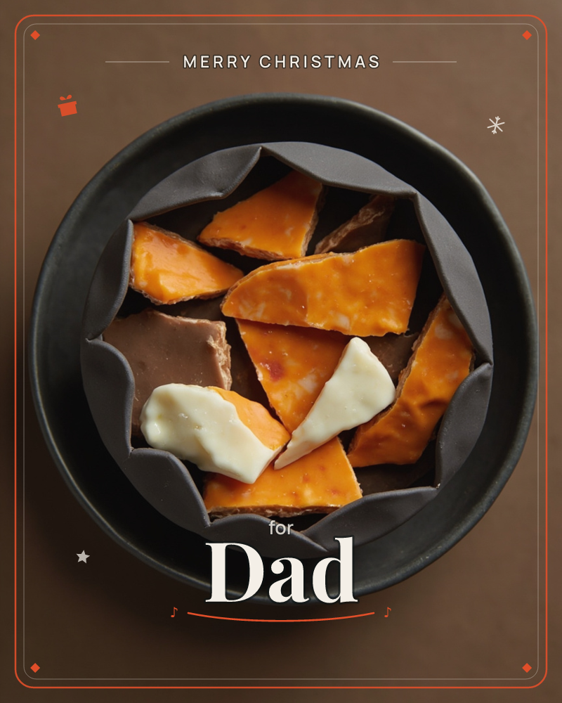 A dark scalloped ceramic dish sits nested in a matching round plate, filled with jagged shards of amber toffee, milk chocolate, and pale creamy fudge, a christmas e-card design