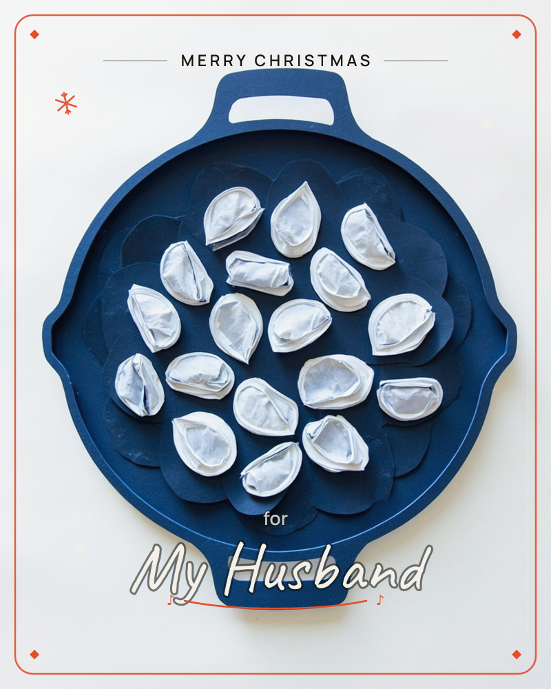 A round navy skillet with two stubby handles sits centred on a plain white background, filled with a cluster of pale silvery-white dumplings cut from…, a christmas e-card design