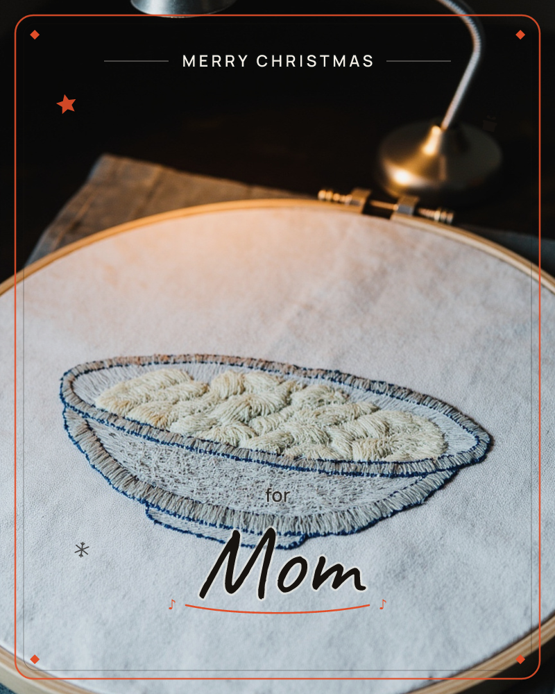 A wooden embroidery hoop holds a piece of pale linen stitched with a bowl of rice, worked in navy outline thread and looped cream stitches that give…, a christmas e-card design