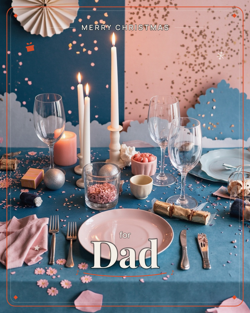 A festive table is set with a pale pink plate, wine glasses and cutlery on a deep teal cloth scattered with confetti and paper crackers, a christmas e-card design