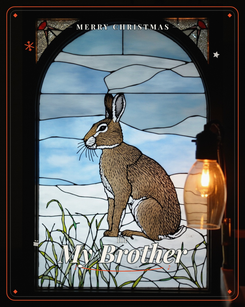 An arched stained-glass panel shows a brown hare sitting alert among tall grass, its long ears raised against a pale winter sky pieced from icy blue…, a christmas e-card design