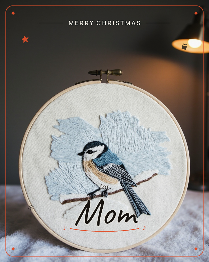 An embroidery hoop holds a stitched chickadee perched on a snow-dusted branch, its blue-grey wings and buff belly worked in fine thread against pale…, a christmas e-card design