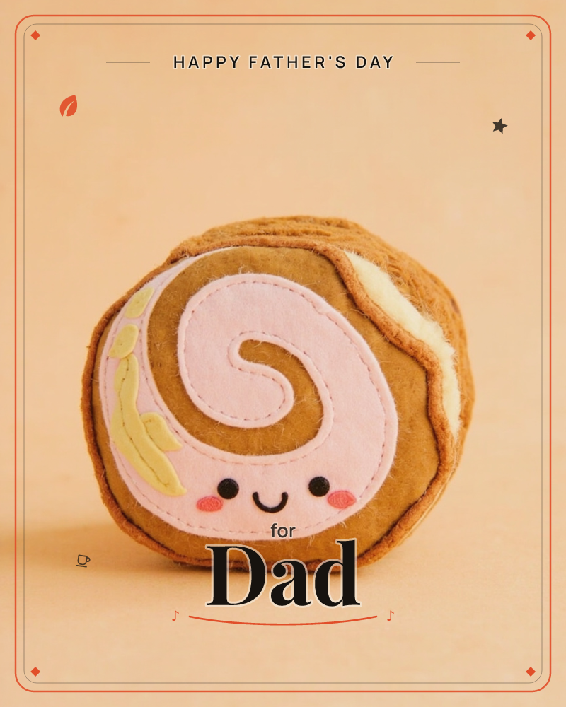 A plush swiss-roll slice with a stitched pink swirl face sits against a soft peach background, its felted fabric texture catching a gentle, even light, a fathersday e-card design