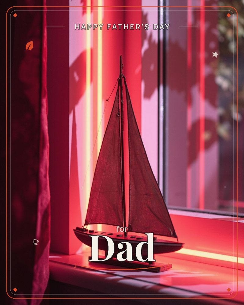 A small wooden model sailboat sits on a windowsill, its cloth sails glowing deep red as low sunlight streams through the glass behind it, a fathersday e-card design