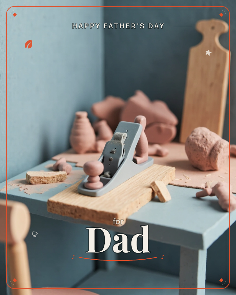 A miniature woodworking bench sits in a muted blue corner, cluttered with terracotta clay shapes, a wooden cutting board, and a small grey hand plane…, a fathersday e-card design