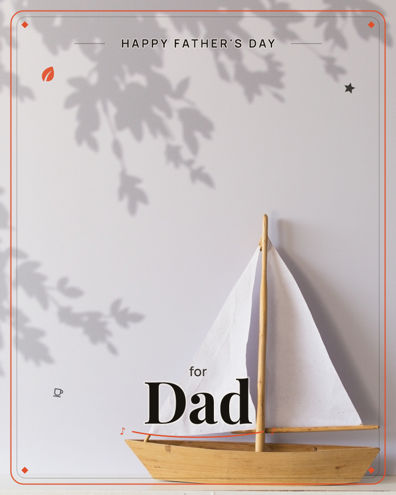 A small wooden toy sailboat with white cloth sails sits against a plain grey wall, its surface dappled with the soft shadow of leafy branches falling…, a fathersday e-card design