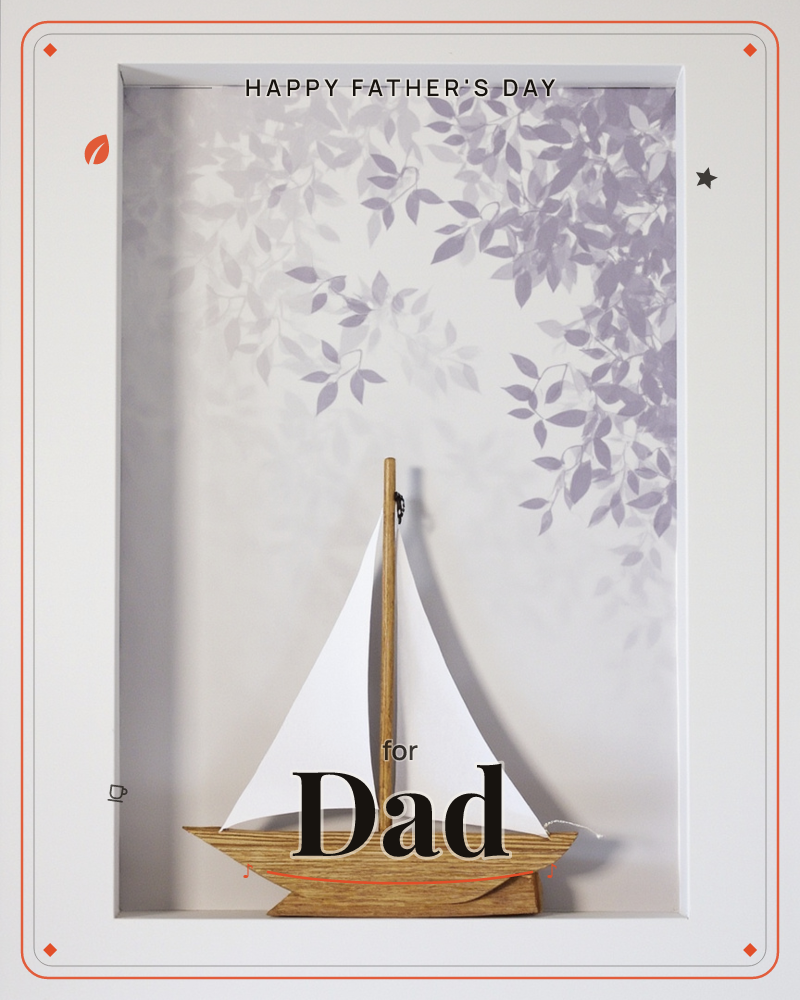 A small wooden sailboat with pale paper sails sits inside a shadow-box frame, set against a soft mauve-grey wallpaper of trailing leaf silhouettes, a fathersday e-card design