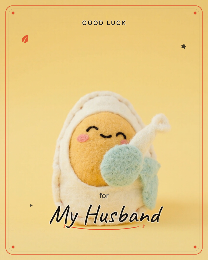 A felt figure shaped like a swaddled baby sits against a soft yellow background, its rosy-cheeked face peeking out from a cream wrapped covering, a good luck e-card design