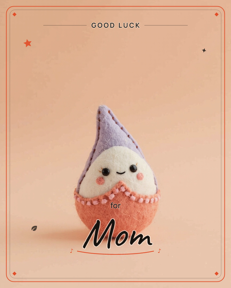 A small felt gnome-like figure stands alone against a soft peach background, its round body stitched in coral and cream with a tall lavender hood, a good luck e-card design