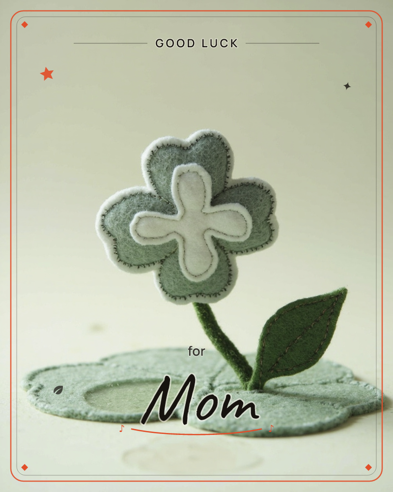 A single flower cut and stitched from soft sage-green felt stands upright on a matching felt base, its white cross-shaped centre echoed in a smaller…, a good luck e-card design