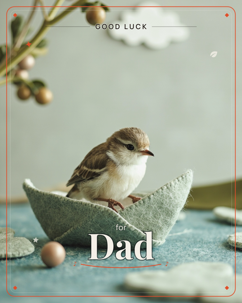 A small sparrow perches inside a felt boat shaped like folded paper, sailing on a textured blue-grey surface dotted with felt pebbles and stones, a good luck e-card design