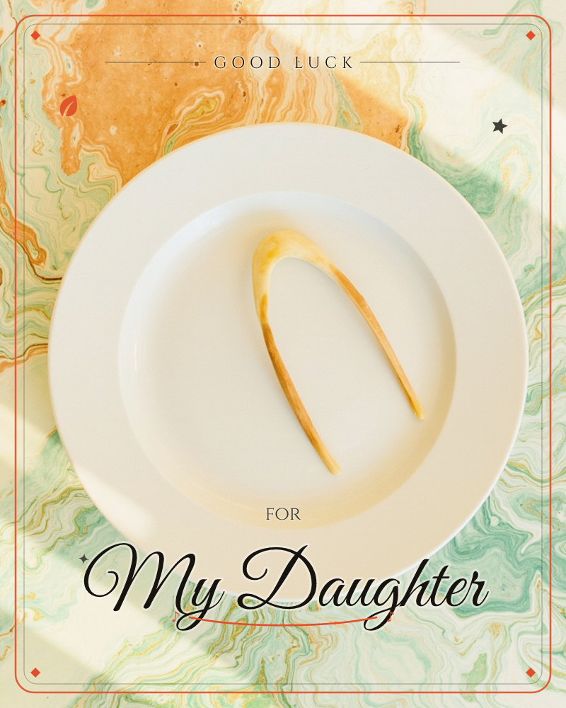 A single wishbone rests on a plain white plate, set atop a marbled tabletop swirled in green and amber, a good luck e-card design