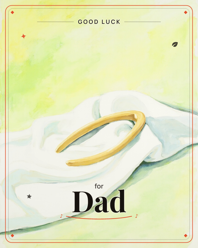 A gold horseshoe-shaped bangle rests on a soft white cloth, its folds catching pale blue-grey shadows, a good luck e-card design