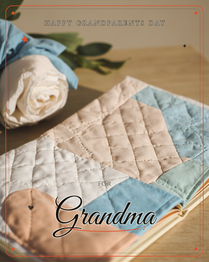 A quilted fabric notebook cover in patchwork blocks of dusty blue, cream and blush lies on a wooden table beside a fabric flower wrapped in pale blue…, a grandparents day e-card design