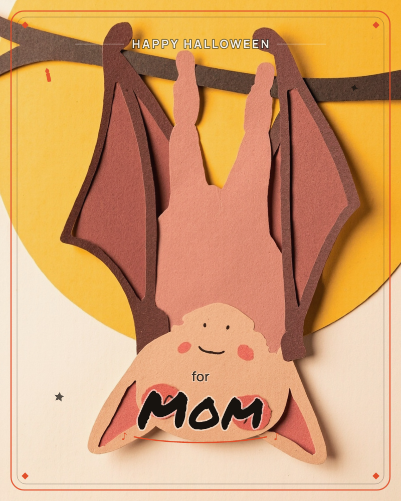 A cheerful paper-cut bat hangs upside down from a dark branch, wings folded against a mustard-yellow moon on a cream background, a halloween e-card design