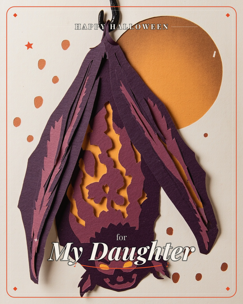 A layered paper-cut bat hangs upside down with wings folded like a cloak, its body carved into an intricate lace pattern that glows amber against a…, a halloween e-card design