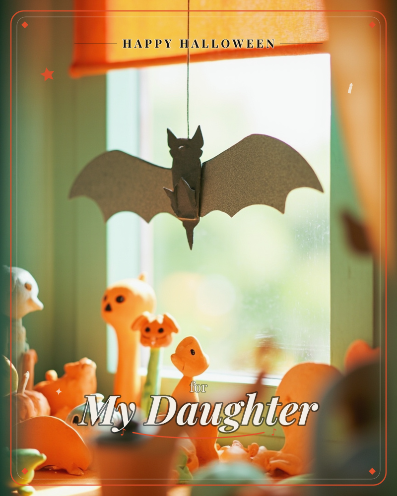 A black paper bat with folded wings hangs on a thread in front of a sunlit window, its shadow soft against the glass, a halloween e-card design
