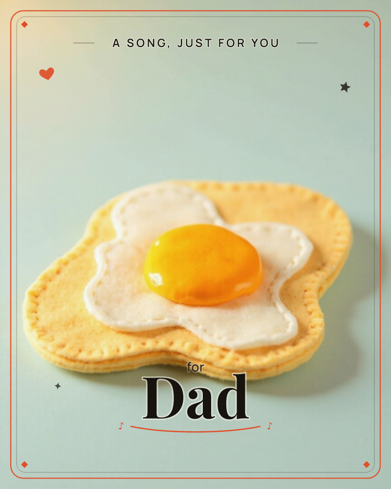 A fried egg made from stitched felt sits alone on a pale blue-grey surface, lit softly from above, a just because e-card design