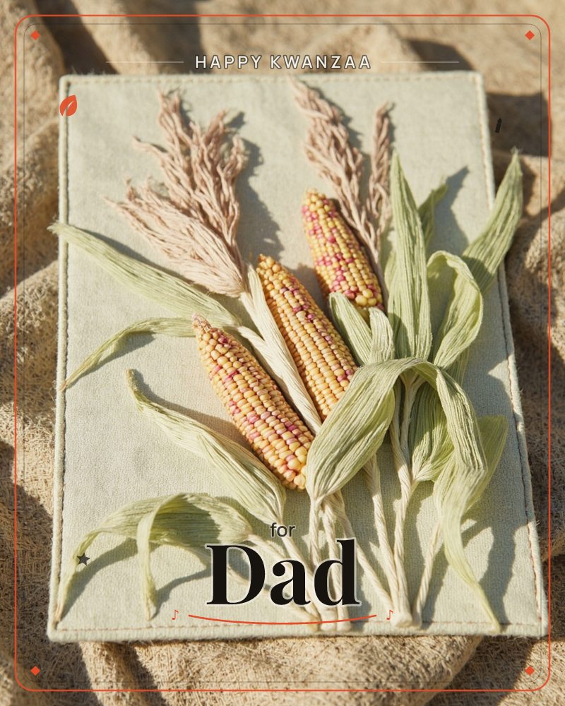 A stitched fabric card shows three ears of speckled corn bundled with pale husks and feathery dried grasses, arranged against a sage-green textile…, a kwanzaa e-card design