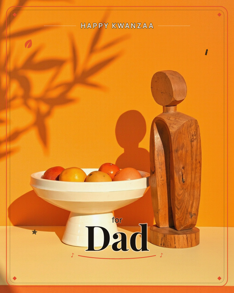 A still life glows against a warm orange wall, where a pale ceramic pedestal bowl of apples and citrus sits beside a carved wooden figure with a…, a kwanzaa e-card design
