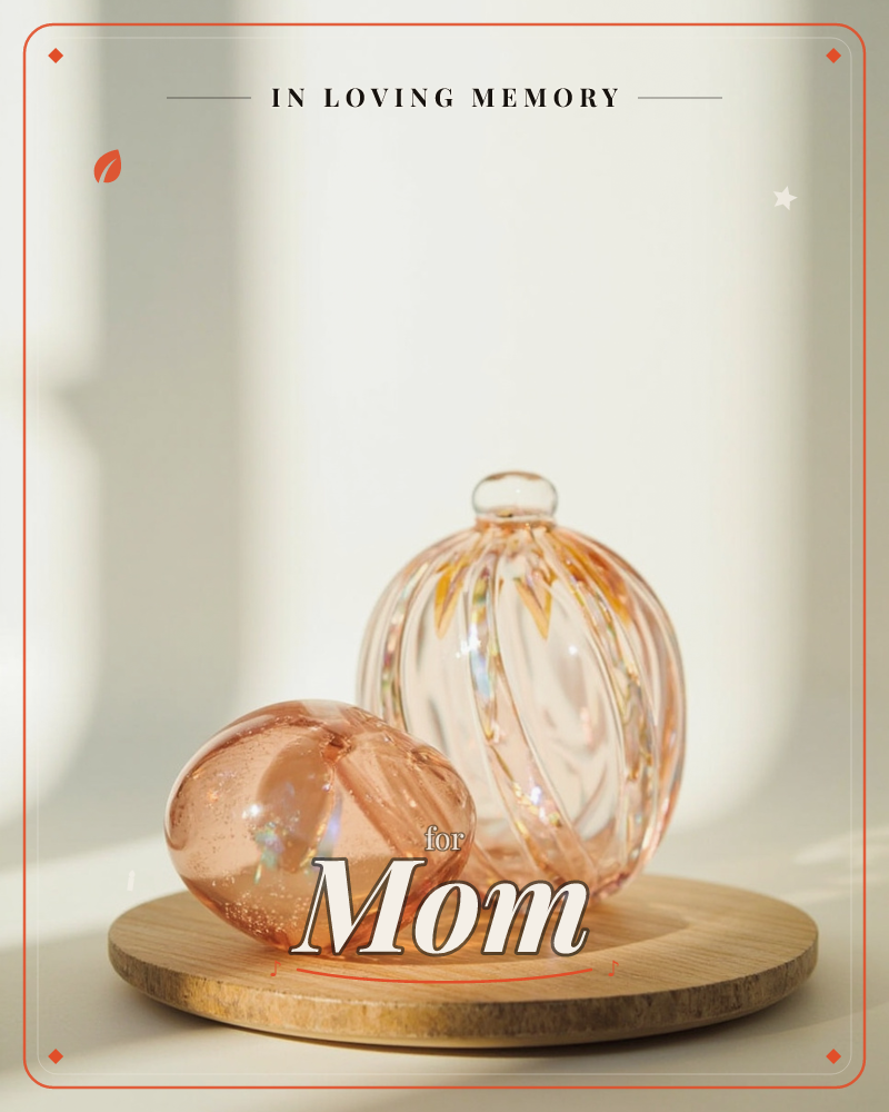 Two blown-glass ornaments, one round with fine ribbed stripes and one squat teardrop shape, sit together on a light wooden coaster against a soft…, a memory e-card design
