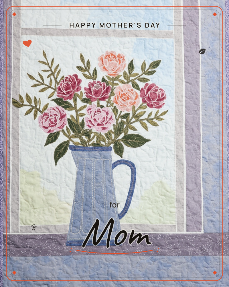 A quilted textile illustration shows a blue pitcher filled with roses in pink, coral and rose tones, set on a windowsill against a soft sky backdrop, a mothersday e-card design