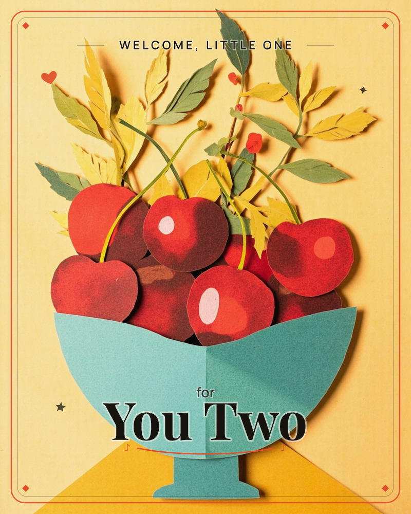 A paper-craft still life shows a teal pedestal bowl overflowing with deep red cherries, cut from layered card and folded into rounded, glossy shapes, a new baby e-card design