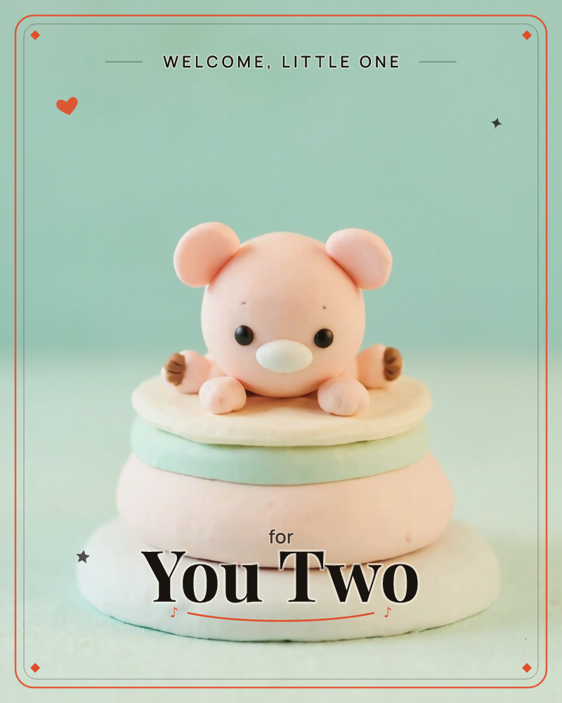 A tiny pink clay bear peeks over the top of a stacked, macaron-like tower of pastel discs, its round paws resting on the edge, a new baby e-card design