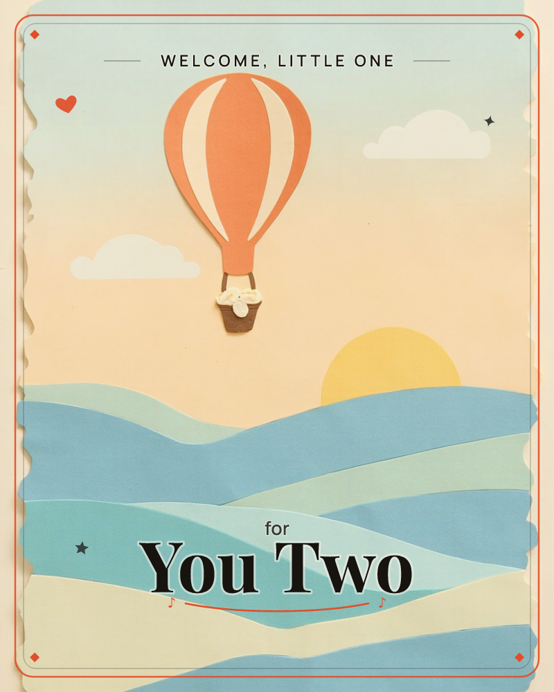 A layered paper-cut illustration shows a terracotta and cream striped hot air balloon drifting over rolling blue hills toward a soft yellow sun, a new baby e-card design