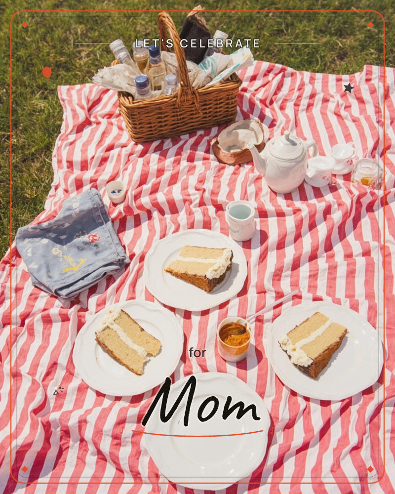 A red-and-white striped picnic blanket is spread on sunlit grass, laid with three slices of frosted layer cake, a white teapot and cups, small jars of…, a party e-card design