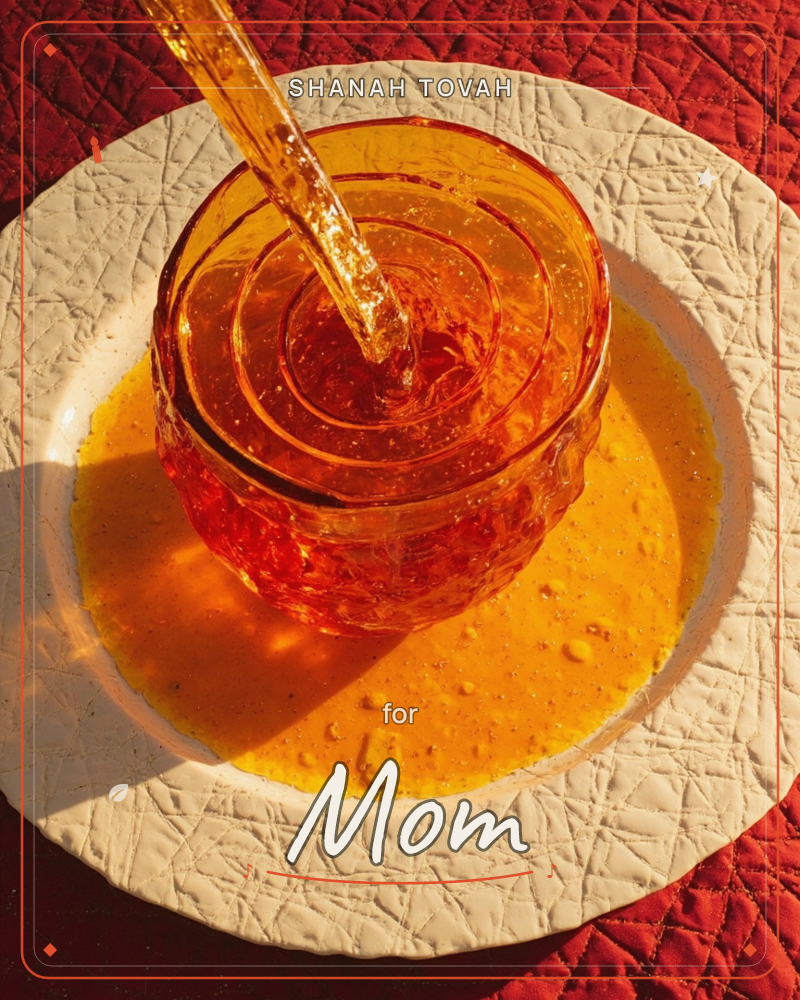 A close-up looks straight down onto a small glass bowl brimming with amber liquid, caught mid-pour as a stream spirals into it and spills over onto a…, a rosh hashanah e-card design