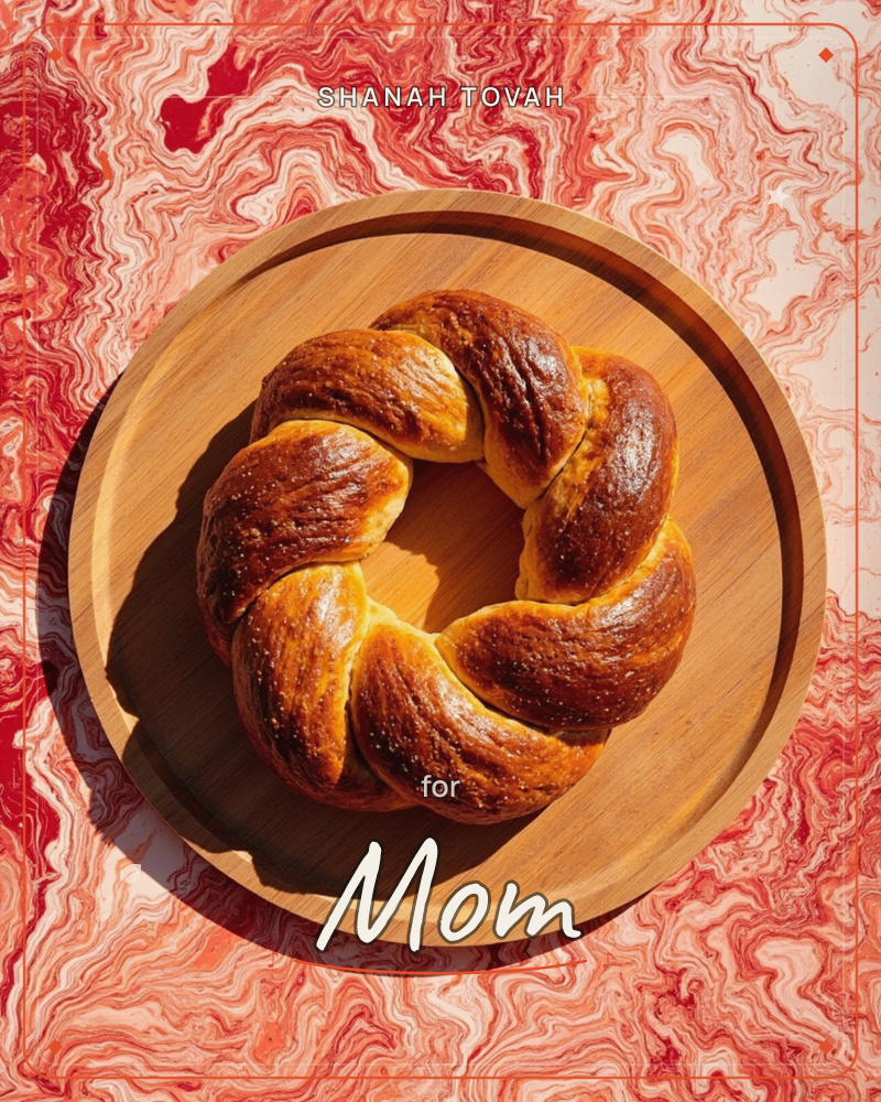 A round braided loaf, glossy and deep golden-brown, sits on a wooden board photographed from directly above, a rosh hashanah e-card design