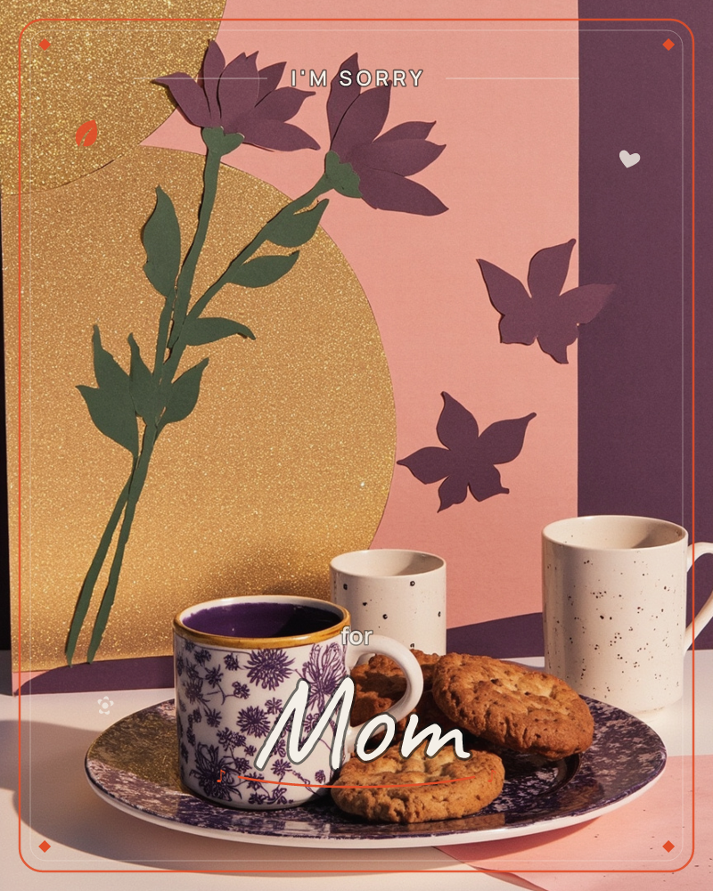 A paper-craft still life sets three mugs and a plate of cookies against a backdrop of cut-paper flowers and falling leaves, with a gold glitter circle…, a sorry e-card design