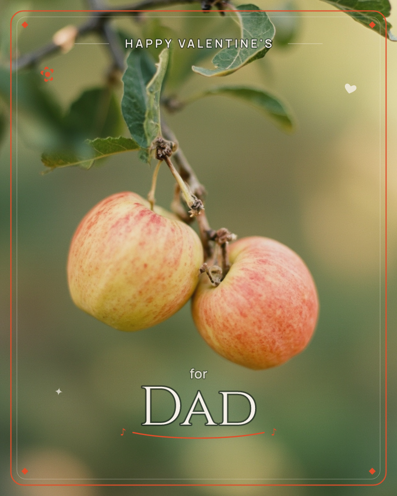 A close-up photograph shows two ripe apples hanging from a leafy branch, their skins blushed with red and gold over a soft green base, a valentine e-card design