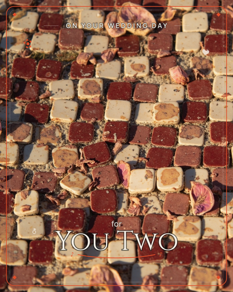 A close-up of a checkerboard tile pathway in deep red and cream squares, scattered with dried, curling flower petals and bits of dead leaves, a wedding e-card design